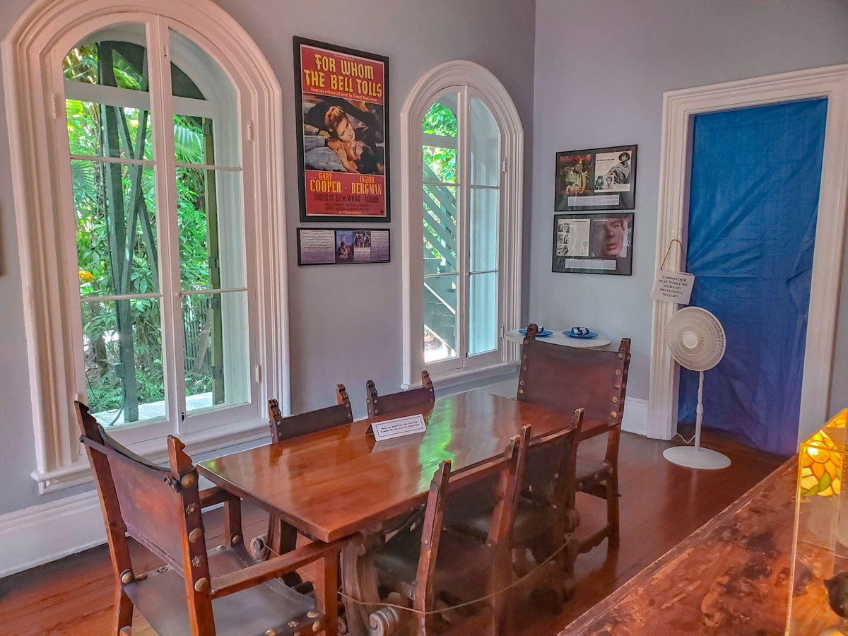 The dining area of Ernest Hemingway's house with wooden chairs and table.