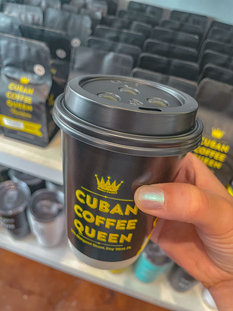 A cup of coffee with text "Cuban Coffee Queen" being held.