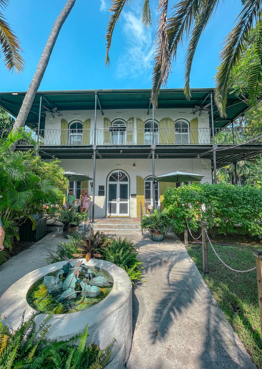The front of Ernest Hemingway's home surrounded by plants and a fountain.