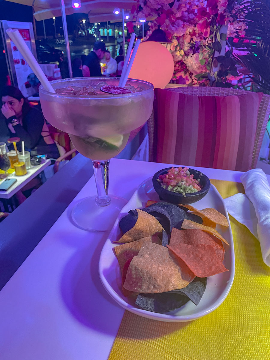 Tacos and salsa on a plate and a big glass of cocktail on the side.