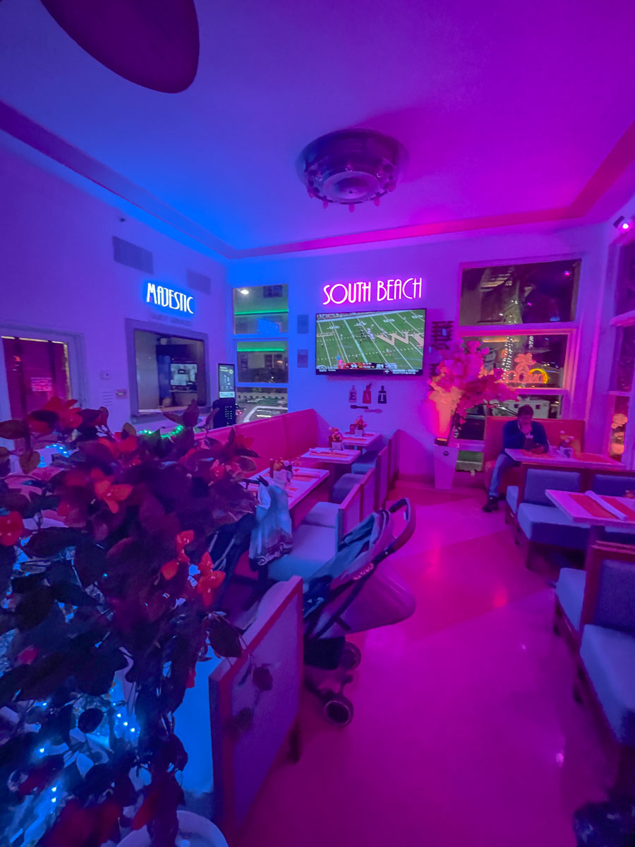 The inside of a restaurant with dark lighting and neon lights.
