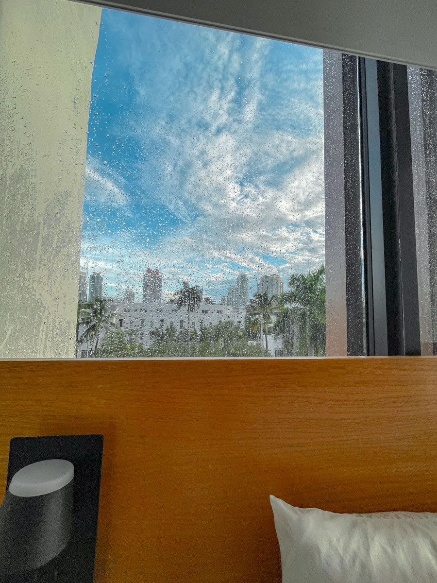 A wet hotel room window with a view of Miami outside.