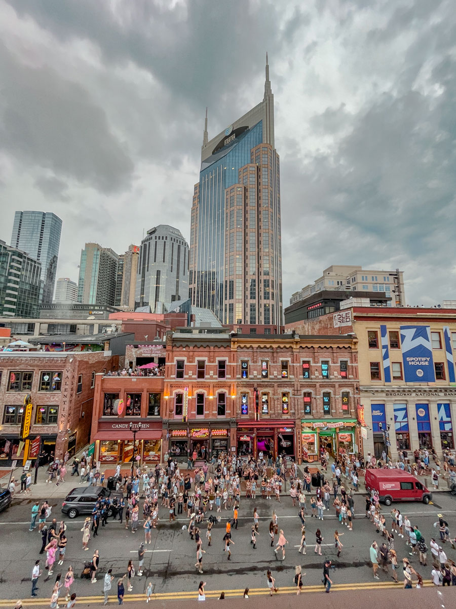 View of Nashville downtown with shops open and people walking on the sidewalks and streets.
