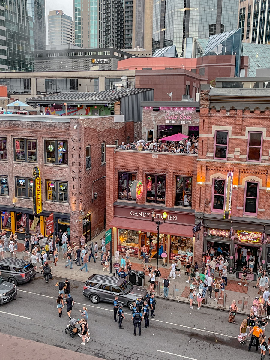 People walking on the streets and sidewalks of downtown Nashville as seen from an upper level of a building.