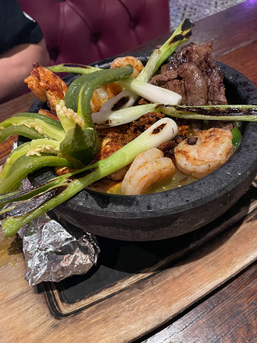 Food on a black bowl on a wooden table.