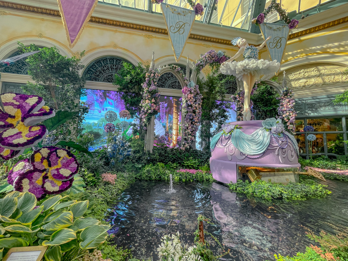 Colorful art and garden exhibit with fountain and ballerina figure displays inside the Bellagio Conservatory & Botanical Gardens in Las Vegas.