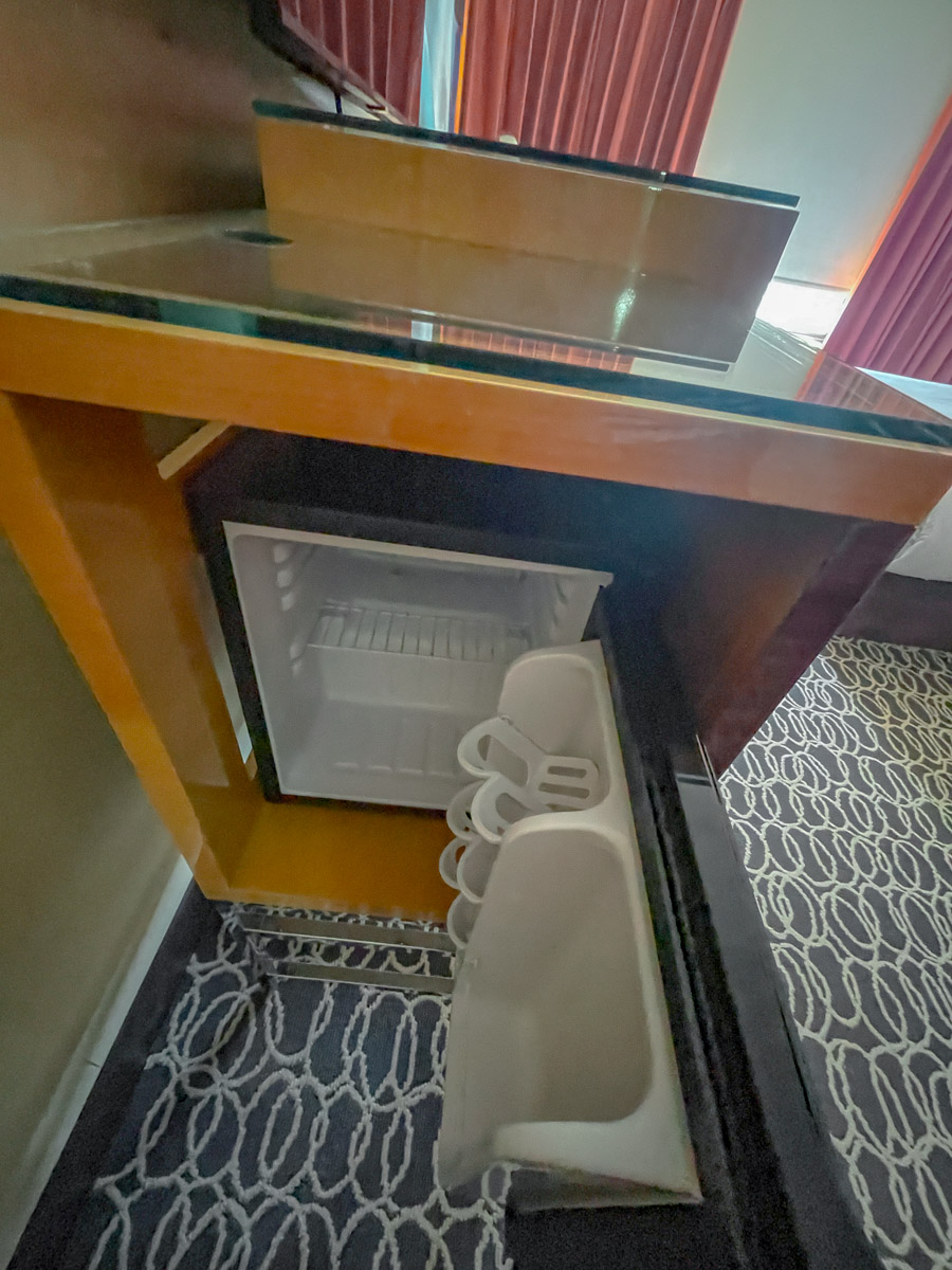 A small refrigerator under a hotel table.