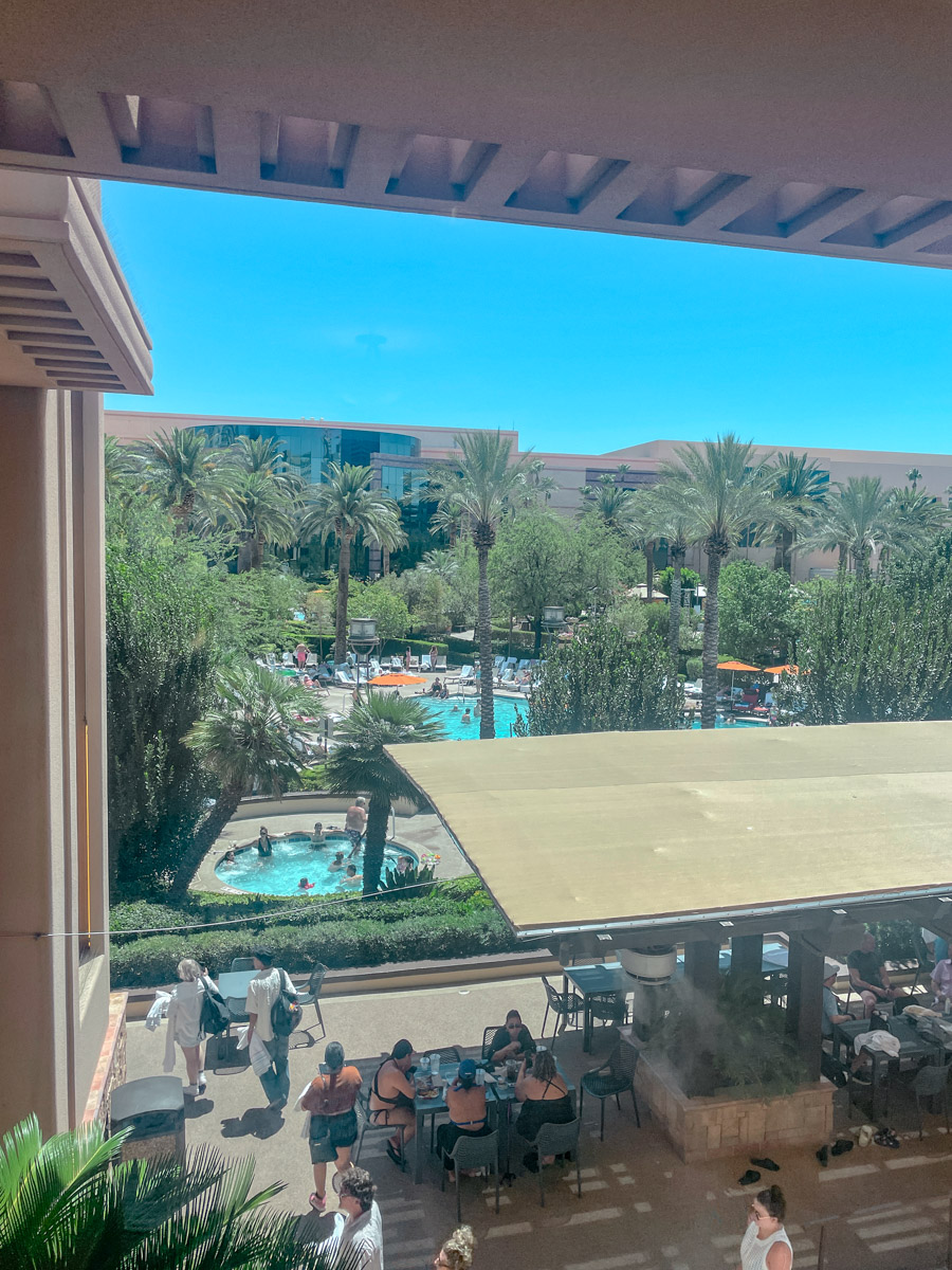 The pool area of MGM Grand hotel in Las Vegas with swimming pools, palm trees, plants, and people.
