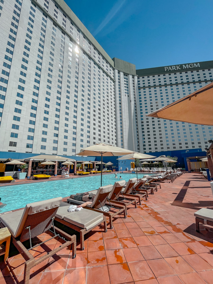 Rows of sun beds by a swimming pool and with the Park MGM building in the background.