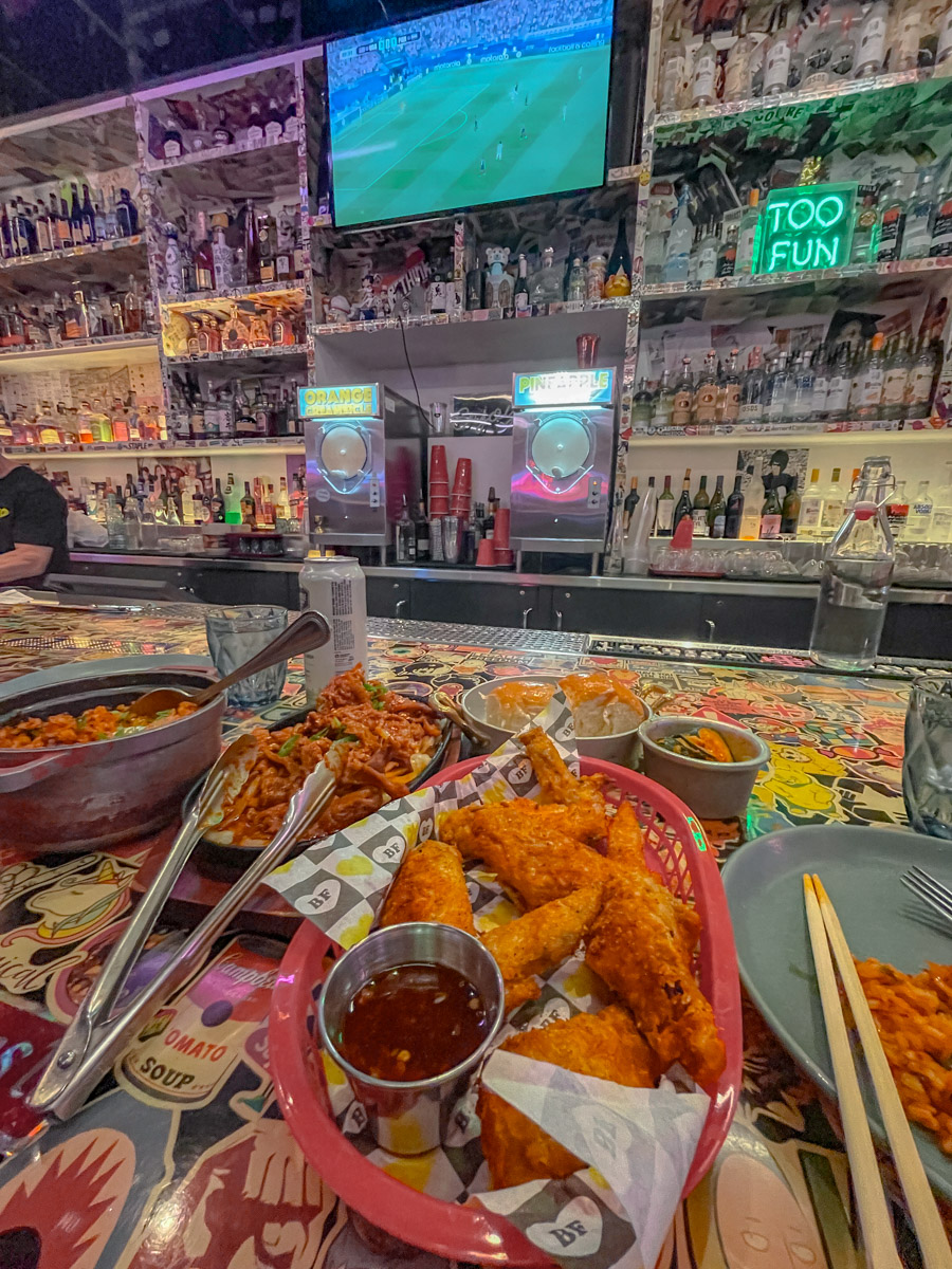 Food on a table with stickers and bar shelves with bottles inside Park MGM Las Vegas.