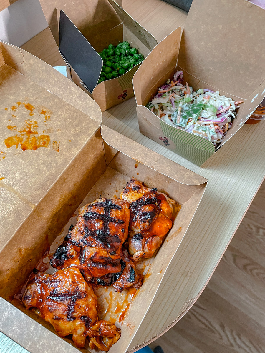 Servings of salad and grilled meat packed in takeaway boxes.