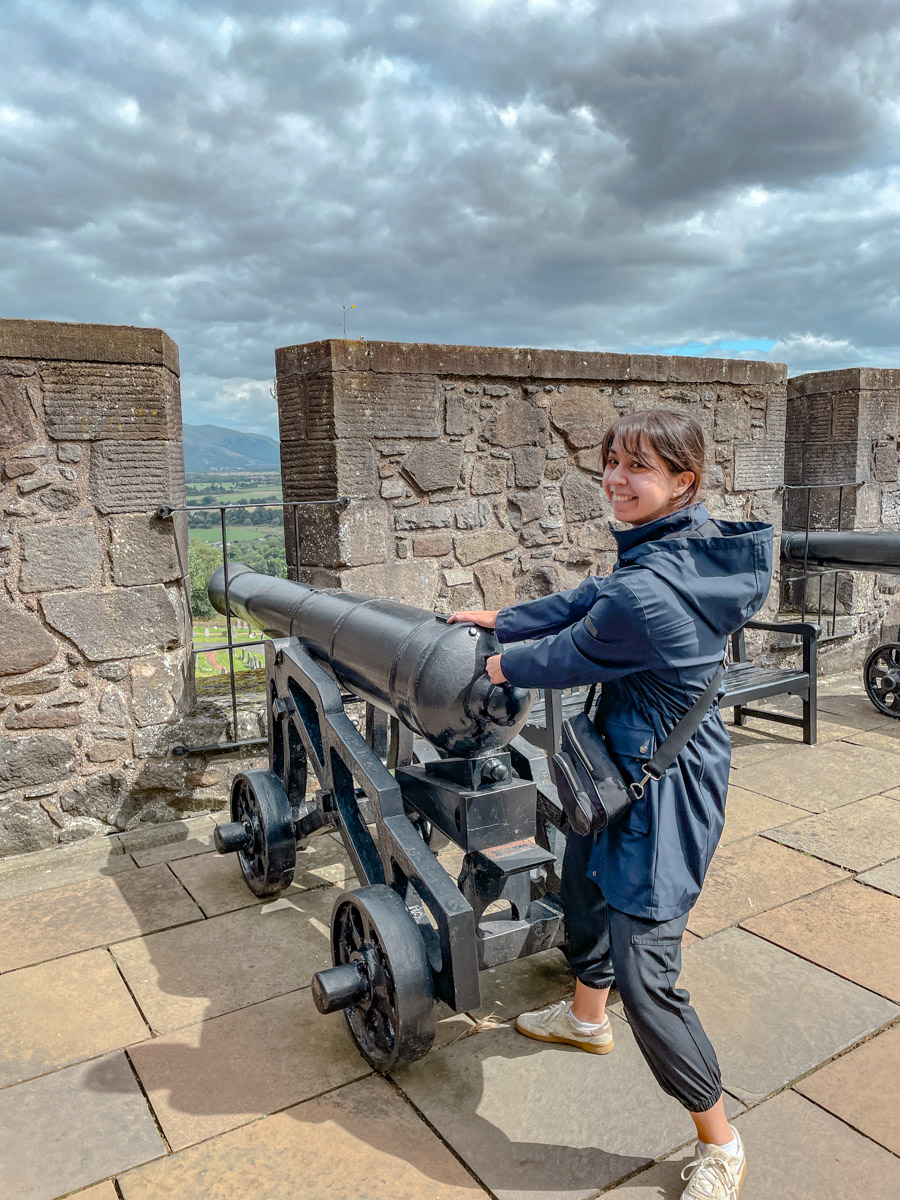 A woman standing by an iron cannon in Stirling Castle.