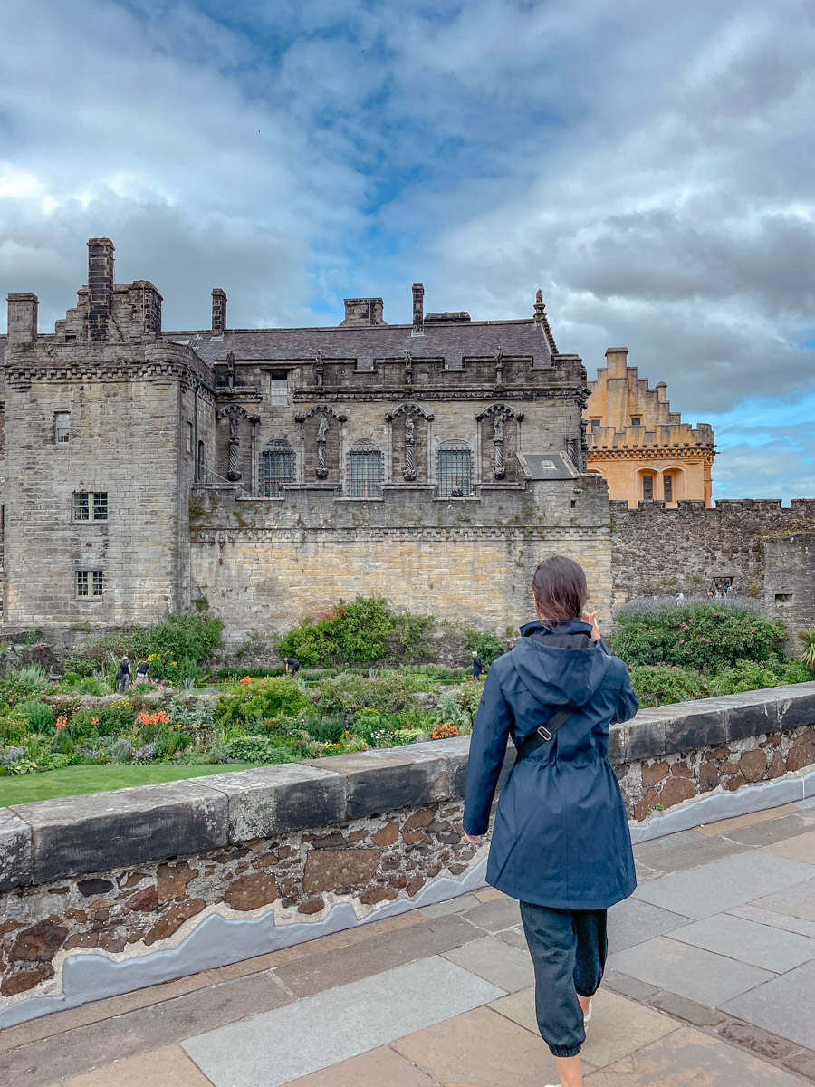 A woman standing on a bridge in front of Stirling Castle.