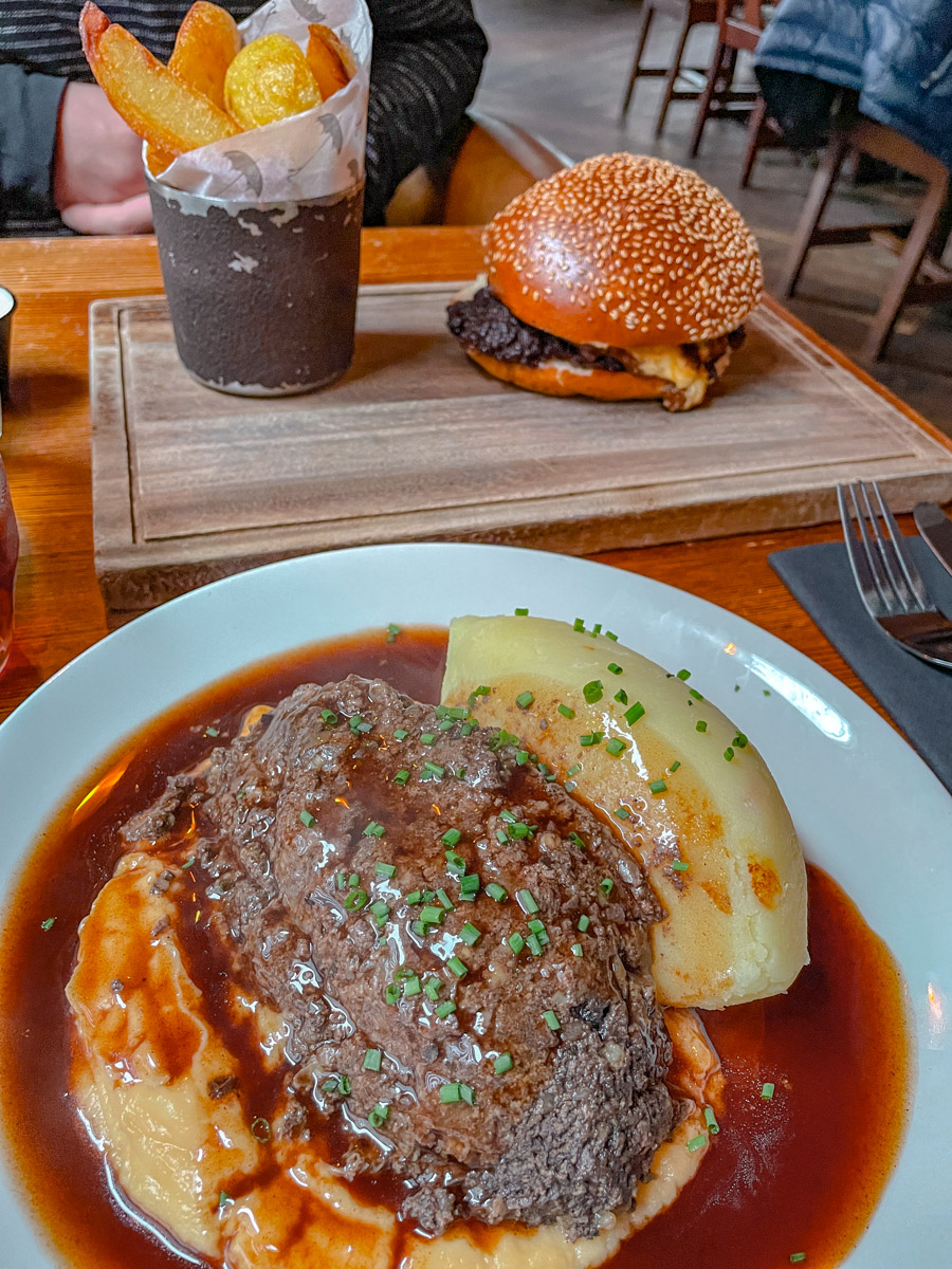 Servings of burgers and fries and steak and mashed potatoes.