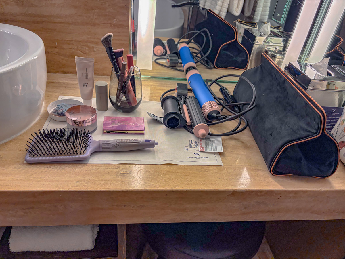 Makeup and hair tools neatly arranged in a hotel room counter.
